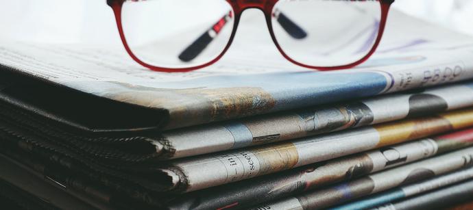 Bild eines Stapels von Zeitungen mit Brille obenauf